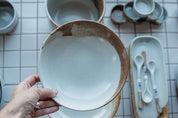 A hand holding a handmade breakfast bowl in blue and brown